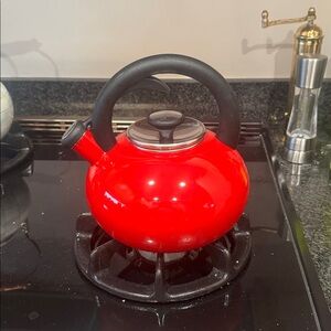 sur la table Red Whistling Tea Kettle with Black Handle